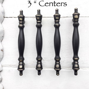 May include: Four black cabinet pulls with gold accents. The pulls are 3 inches apart.