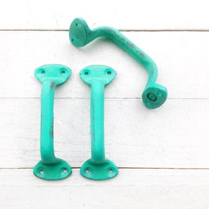 May include: Three turquoise metal door handles. Two are straight and one is curved.
