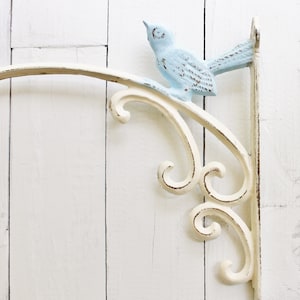 May include: White metal shelf bracket with a decorative scroll design and a light blue bird perched on the top.