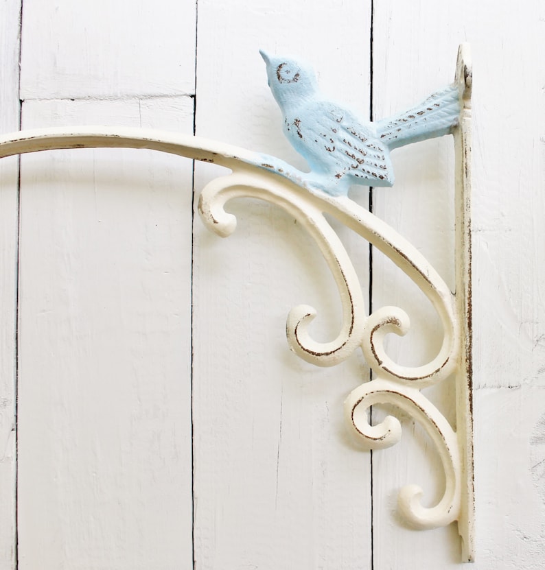 May include: White metal shelf bracket with a decorative scroll design and a light blue bird perched on the top.