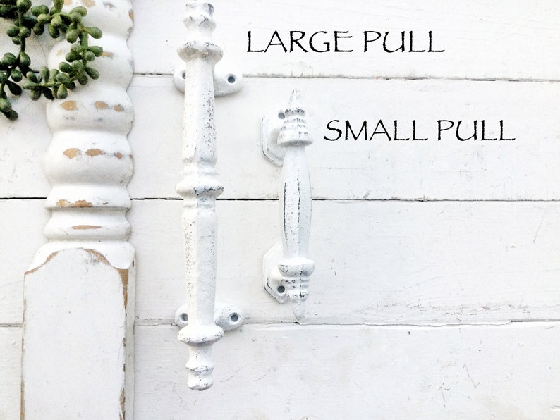 May include: Two white, distressed-finish pull handles, one large and one small, are displayed against a white, wooden background. The text "LARGE PULL" and "SMALL PULL" are above the respective handles. The handles are likely for furniture.