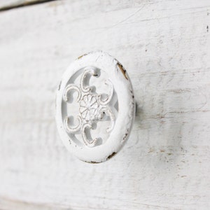 May include: White oval-shaped cabinet knob with a decorative floral design.