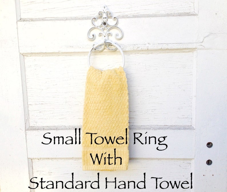Peut inclure: Un petit anneau de serviette blanc avec un motif d&eacute;coratif enroul&eacute;, tenant une serviette de toilette jaune. Le texte "Small Towel Ring With Standard Hand Towel" est sous la serviette.