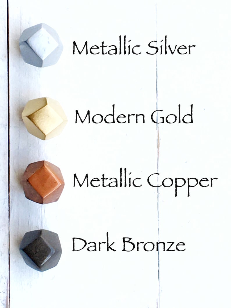 May include: Four geometric cabinet knobs in different metallic finishes: silver, gold, copper, and bronze. The knobs are arranged vertically on a white background.