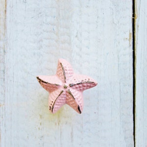May include: A pink starfish-shaped cabinet knob with a distressed finish.