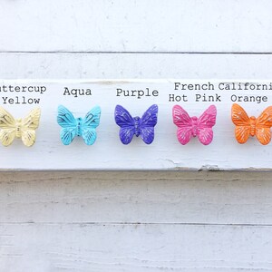 May include: Assortment of eight butterfly drawer pulls in various colors, including blushing pink, buttercup yellow, aqua, purple, hot pink, orange, and nautical blue.