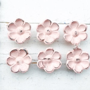 May include: Six pink flower-shaped drawer pulls with a distressed finish.