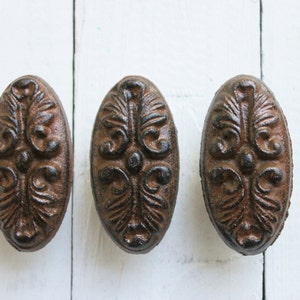 May include: Three oval-shaped cast iron drawer pulls with a dark brown finish. Each pull features a detailed floral design.
