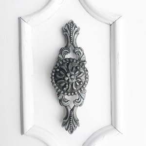 May include: A silver ornate cabinet knob with a floral design.