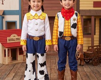 May include: Two children wearing cowboy-themed costumes. One wears a white long-sleeve shirt with yellow shoulder accents, two silver buttons, and blue pants with cow-print flare bottoms. The other wears a yellow plaid shirt, white cow-print vest, red bandana, and blue pants.