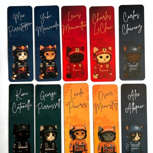 May include: A collection of ten rectangular bookmarks featuring cartoon cats dressed as Formula 1 drivers. Each bookmark has a driver's name and a team logo, with backgrounds in various colors like blue, red, and orange.