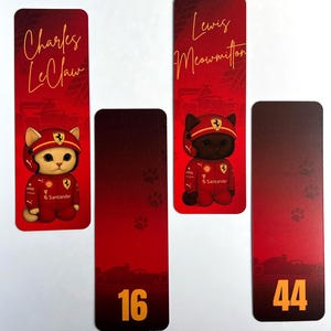 May include: Four red bookmarks featuring cartoon cats in racing attire. Two bookmarks have the names "Charles LeClaw" and "Lewis Meowmilton" in gold script. The other two have the numbers "16" and "44". The cats wear red racing suits.
