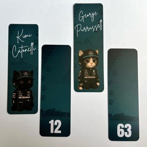 May include: Four bookmarks with a teal background. Two bookmarks feature a black cat and a gray and white cat wearing a racing uniform and cap. The other two bookmarks have the numbers 12 and 63. The names "Kimi Catonelli" and "George Purrussell" are written on the bookmarks.