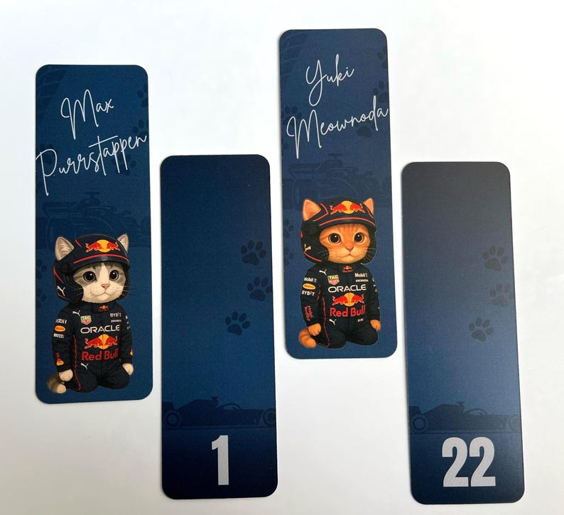 May include: Four bookmarks with a racing theme. Two bookmarks feature a cat in a racing suit and helmet with the names "Max Purrstappen" and "Yuki Meownada". The other two bookmarks have the numbers "1" and "22". All are on a blue background.