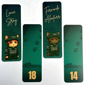 May include: Four green bookmarks with gold text and illustrations. Two bookmarks feature a cat wearing a racing suit and helmet, with the names "Lance Stray" and "Fernando Alonfurr". The other two have the numbers "18" and "14".