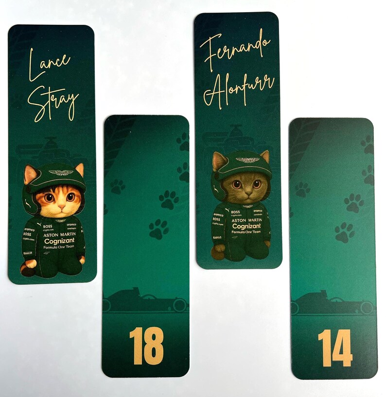 May include: Four green bookmarks with gold text and illustrations. Two bookmarks feature a cat wearing a racing suit and helmet, with the names "Lance Stray" and "Fernando Alonfurr". The other two have the numbers "18" and "14".
