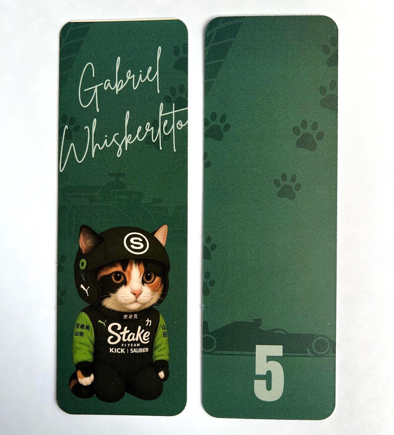 May include: Two green bookmarks. One features a cat wearing a racing suit and helmet with the text "Gabriel Whiskerteto". The other has paw prints and a race car with the number 5.