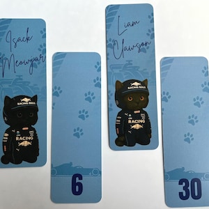 May include: Four blue rectangular bookmarks with rounded corners. Two bookmarks feature a black cat wearing a racing uniform and a cap. The text "Isack Meowjar" and "Liam Clawson" are written above the cat images. The other two bookmarks have the numbers 6 and 30.