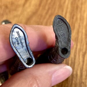 May include: Close-up of the feet of a black action figure. The soles of the feet are visible, with the text "2008 Hasbro China" imprinted on one foot. The other foot has a similar imprint. The figure is held by a person.