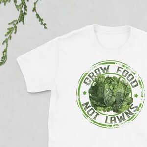 May include: White t-shirt with a green distressed circle graphic that says "Grow Food Not Lawns".