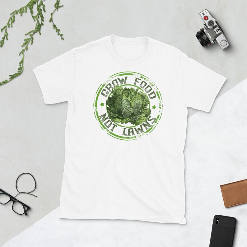 May include: White t-shirt with a green distressed circle graphic that says "Grow Food Not Lawns".