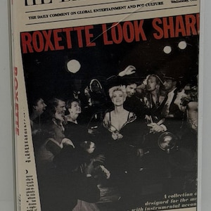 Puede incluir: Una cinta de casete de Roxette "Look Sharp!". La portada presenta una imagen en blanco y negro de la banda y el texto "HE DAILY ROXET" y "ROXETTE LOOK SHARP!" en rojo y blanco.