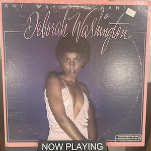 May include: A vintage vinyl record album cover for Deborah Washington, titled "Any Way You Want It." The cover shows a woman in a pink dress against a purple backdrop. The words "NOW PLAYING" are displayed at the bottom.