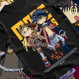 以下が含まれることがあります： 黒いTシャツに、カラフルなアニメのグラフィック。詳細な衣装を着た2人のキャラクターと日本語のテキストがデザインされています。日本語の文字が入った黄色の正方形もあります。このTシャツは柔らかい素材で作られています。