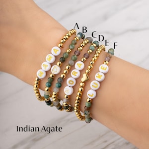 May include: Six beaded bracelets with white letter beads spelling out "MAMA", "NORA", and "LUKE". The bracelets also feature gold beads and Indian agate stones. The text "Indian Agate" is at the bottom.