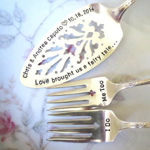May include: Two silver forks and a silver cake server with engraved text. The forks say "I Do" and "Me Too". The server says "Chris & Andrea Caputo 10.18.2014 Love brought us a fairy tale..."
