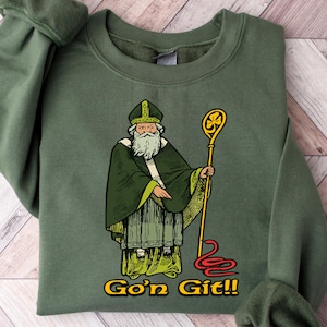 May include: Military green sweatshirt featuring a graphic of a saintly figure in green robes, holding a gold staff. The text "Go'n Git!!" is printed in yellow. The sweatshirt has long sleeves with ribbed cuffs.