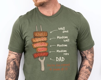 Könnte beinhalten: Olivgrünes T-Shirt mit einer Grafik der Garstufen von Steak auf einer Gabel. Der Text lautet "Well done, Medium well, Medium, Medium rare, DAD". Ein lustiges Geschenk für Grillfans.