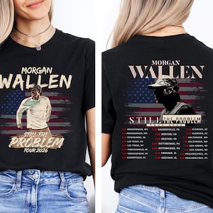 May include: Black t-shirt featuring the text "MORGAN WALLEN" above an image of a person in front of an American flag design. The shirt also displays "STILL THE PROBLEM TOUR 2026". The back of the shirt has the same design.