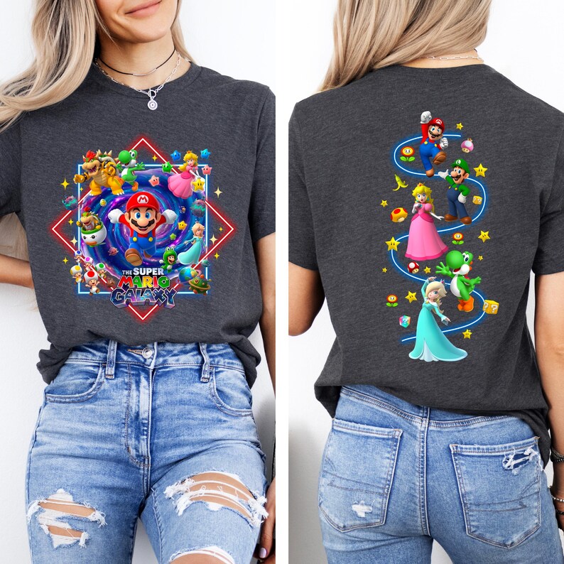 May include: Dark gray t-shirt featuring a colorful graphic of Super Mario characters. The front design includes Mario in the center, surrounded by other characters and the text "The Super Mario Galaxy". The back has a vertical design with Mario, Luigi, Princess Peach, Yoshi, and Elsa.