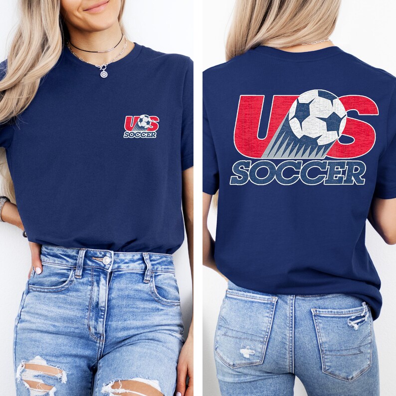 Puede incluir: Una camiseta azul marino con un peque&ntilde;o gr&aacute;fico en el pecho izquierdo que dice US SOCCER con un bal&oacute;n de f&uacute;tbol. La parte posterior de la camiseta muestra un gr&aacute;fico grande con el texto rojo US, un bal&oacute;n y el texto blanco SOCCER debajo.