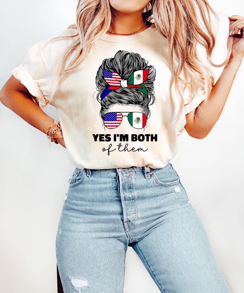 Może przedstawiać: Kremowy t-shirt z napisem "YES I'M BOTH of them". Grafika przedstawia fryzurę z opaską i okularami przeciwsłonecznymi, oba ozdobione flagami amerykańską i meksykańską. Kobieta ma na sobie dżinsy.