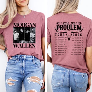 May include: A mauve-colored t-shirt featuring a black and white image of Morgan Wallen and the text "MORGAN WALLEN". The back of the shirt displays "STILL THE PROBLEM TOUR 2026" with a bull skull graphic and tour dates.