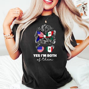 Może przedstawiać: Czarny t-shirt z napisem "YES I'M BOTH of them". Projekt przedstawia fryzurę kobiety z opaską na włosy i okularami przeciwsłonecznymi, oba zdobione flagami amerykańskimi i meksykańskimi.