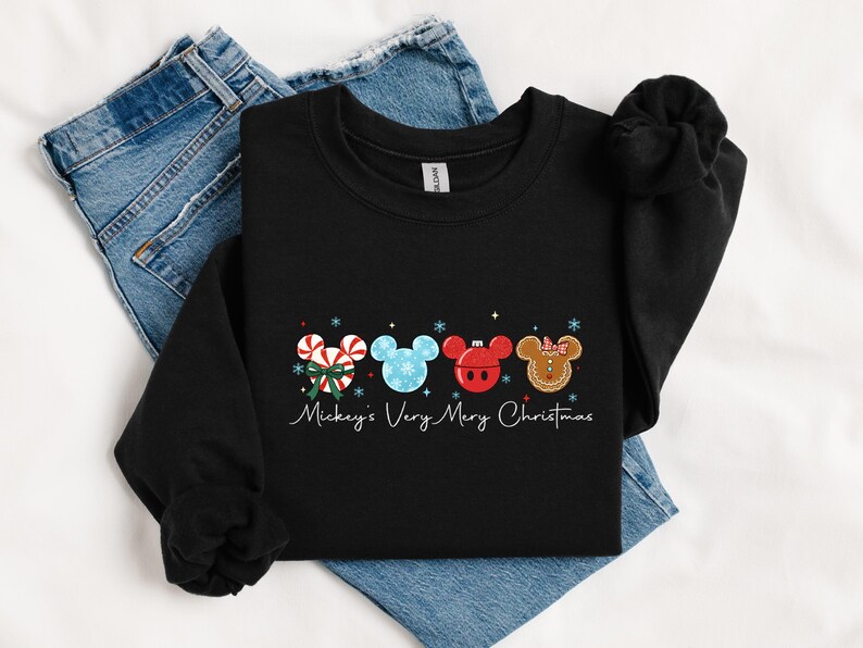 May include: Black crewneck sweatshirt featuring a festive design with Mickey Mouse-themed Christmas ornaments. The ornaments include candy canes, snowflakes, and gingerbread. The text "Mickey's Very Merry Christmas" is written in cursive.