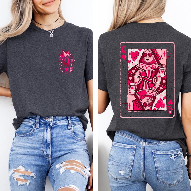 May include: Dark gray t-shirt featuring a pink graphic of a queen of hearts playing card on the back. The front has a small pink design with a crown and the letter "Q". The shirt is paired with blue jeans.