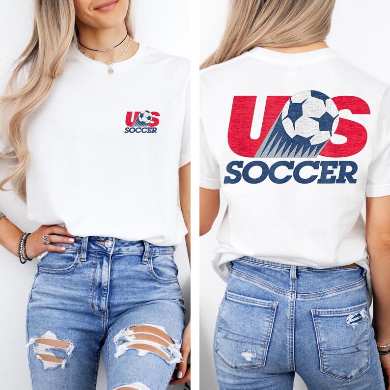Puede incluir: Una camiseta blanca de manga corta con un peque&ntilde;o gr&aacute;fico en el pecho izquierdo con el texto US SOCCER y un bal&oacute;n de f&uacute;tbol. La parte posterior de la camiseta muestra un gr&aacute;fico grande con el texto US SOCCER en rojo y azul con un bal&oacute;n.