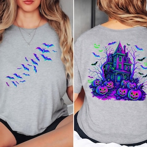 May include: A gray t-shirt featuring a Halloween design. The front of the shirt has a flock of bats in shades of blue and purple. The back of the shirt has a haunted house, pumpkins, and bats in vibrant colors.