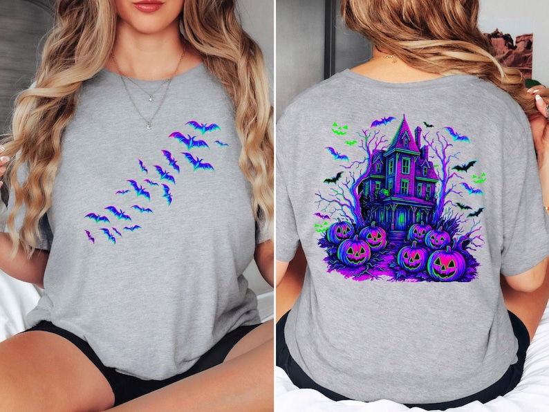 May include: A gray t-shirt featuring a Halloween design. The front of the shirt has a flock of bats in shades of blue and purple. The back of the shirt has a haunted house, pumpkins, and bats in vibrant colors.