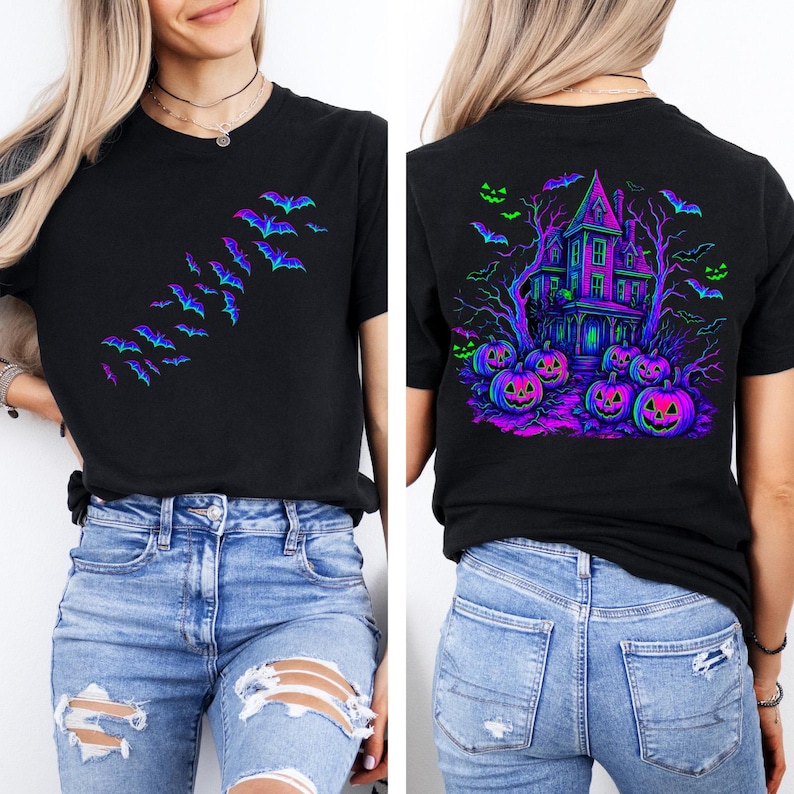 May include: Black t-shirt featuring a Halloween design. The front of the shirt has a flock of bats in shades of blue and purple. The back of the shirt has a haunted house, pumpkins, and bats in neon colors. The shirt is paired with blue jeans.