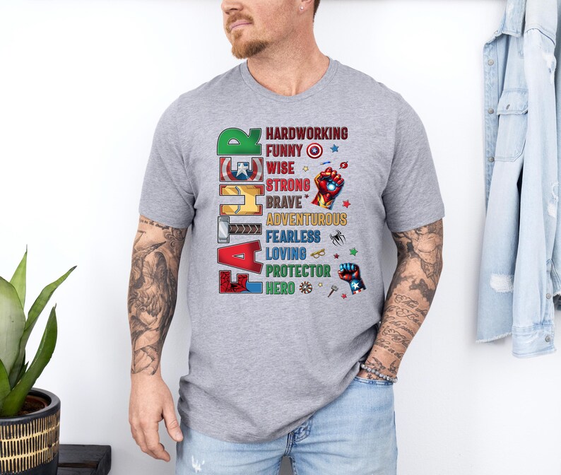 May include: A gray t-shirt with the word "FATHER" in colorful block letters. The shirt features a list of positive attributes like "hardworking," "funny," and "hero," with superhero-themed graphics.