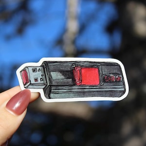 Könnte beinhalten: Handgezeichneter Aufkleber eines USB-Sticks. Der Aufkleber hat einen grau-schwarzen Körper mit roter Akzentuierung und einem roten Quadrat. Der Markenname "SanDisk" ist sichtbar.