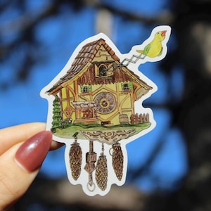 May include: A sticker featuring a whimsical cuckoo clock design. The clock is yellow and brown with a detailed facade, a large clock face, and a small green bird perched above. Three pinecone-shaped weights hang below.