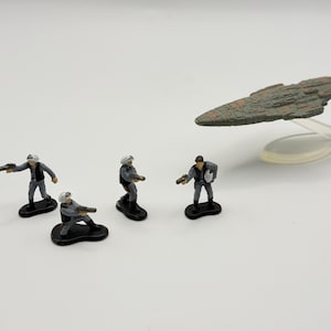 May include: Miniature Star Wars figures and a spaceship model. The figures are dressed in gray and black uniforms, holding blasters. The spaceship is gray and brown, mounted on a clear stand. The scene is set against a white background.