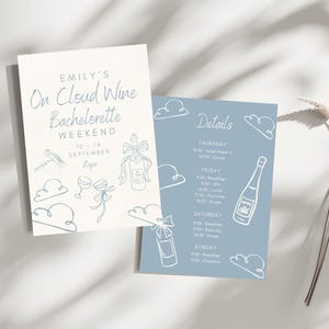 May include: Two invitation cards with a light blue and white color scheme. The cards feature hand-drawn illustrations of wine bottles, glasses, and clouds. Text on the cards includes "Emily's On Cloud Wine Bachelorette Weekend" and event details.