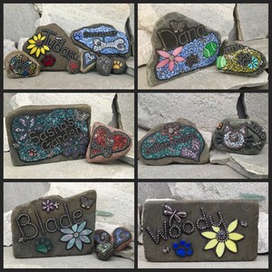 May include: Hand-painted decorative rocks with names, flowers, and paw prints. The rocks feature mosaic designs, butterflies, and the names "Tudas", "Cooper", "Dana", "Sasha's Garden", "Butterscotch", "Blade", and "Woody".